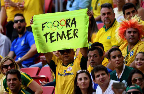 Torcedor segura cartaz no Estádio Mané Garrincha, durante jogo entre Brasil e África do Sul / Foto: Evarista Sa/AFP