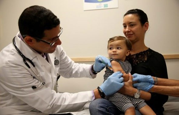 criança recebendo vacina no colo da mãe Joe Raedle/Getty Images