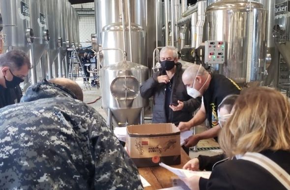 Promotores analisam documentos na sede da cervejaria Backer — Foto: Reprodução